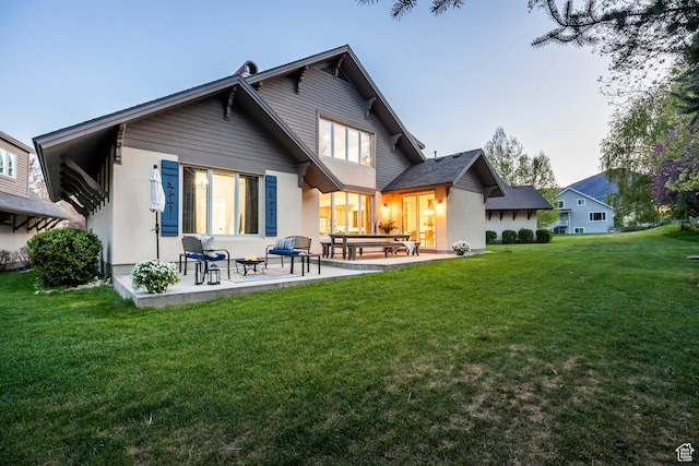 rear view of property with a patio area, a lawn, and stucco siding