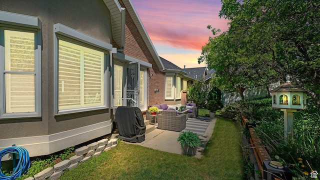 view of side of home with a patio, an outdoor living space, brick siding, and stucco siding