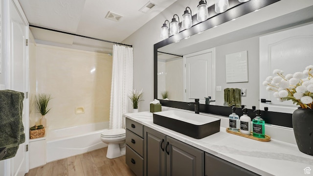 bathroom with toilet, wood finished floors, vanity, and shower / tub combo with curtain