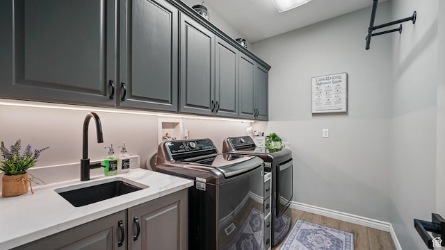 laundry area with independent washer and dryer, cabinet space, wood finished floors, and baseboards