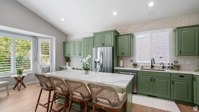 kitchen with green cabinetry, appliances with stainless steel finishes, a sink, vaulted ceiling, and recessed lighting