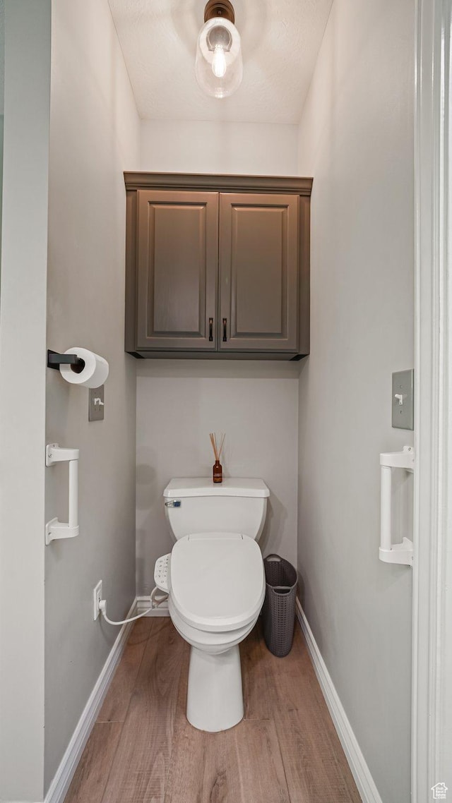 bathroom featuring wood finished floors, baseboards, and toilet