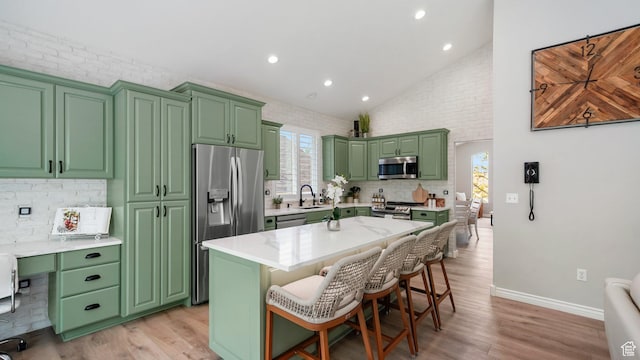 kitchen featuring appliances with stainless steel finishes, green cabinets, light wood-style flooring, recessed lighting, and high vaulted ceiling