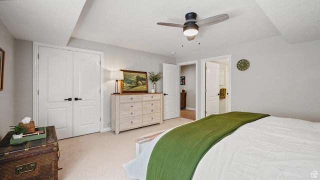 bedroom featuring a closet, light colored carpet, a ceiling fan, and baseboards