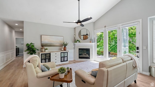 living room featuring light wood finished floors, a glass covered fireplace, ceiling fan, lofted ceiling, and recessed lighting