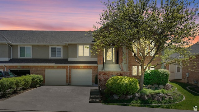 multi unit property with concrete driveway, an attached garage, stucco siding, and brick siding