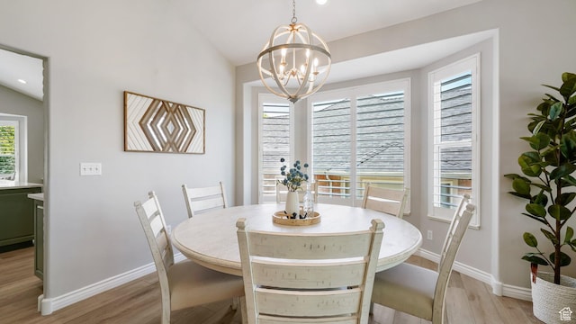 dining area with light wood-type flooring, baseboards, and a chandelier