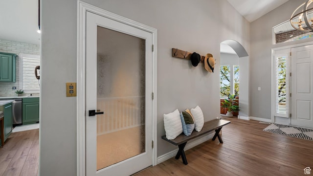 entrance foyer with light wood finished floors, arched walkways, lofted ceiling, and baseboards