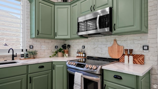 kitchen with appliances with stainless steel finishes, green cabinetry, a sink, and plenty of natural light