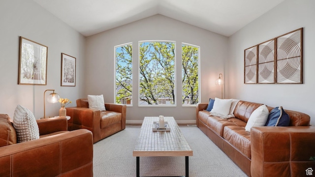 carpeted living area with lofted ceiling and baseboards