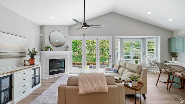 living room with lofted ceiling, ceiling fan, light wood finished floors, a fireplace, and recessed lighting