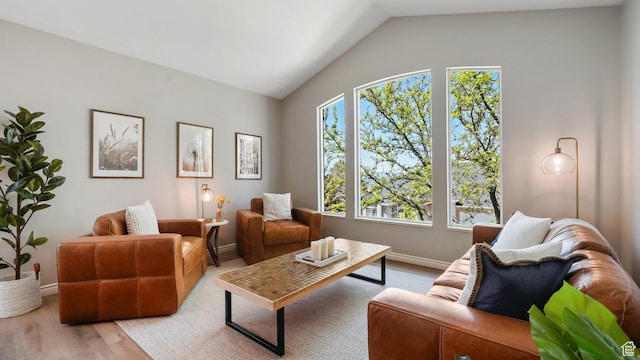 living area with vaulted ceiling, baseboards, and wood finished floors