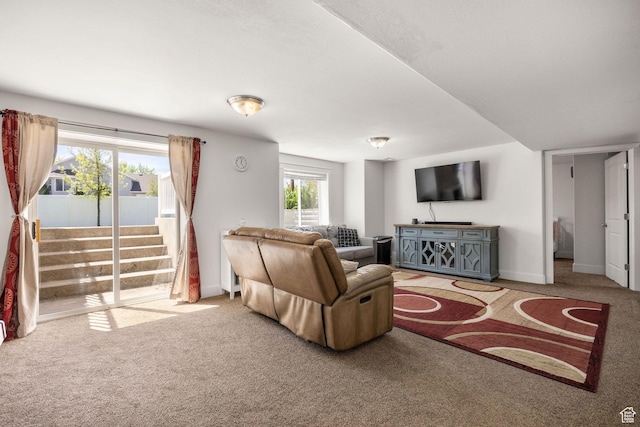 living room featuring carpet floors, baseboards, and stairs