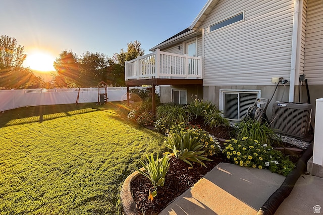 yard at dusk with central AC, fence, and a deck