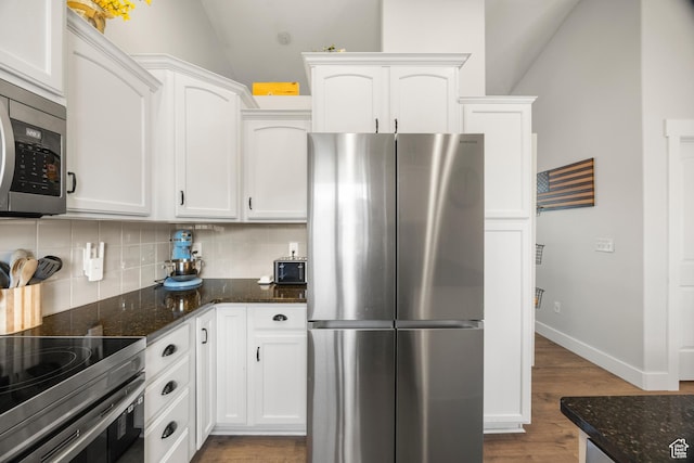 kitchen featuring stainless steel appliances, decorative backsplash, white cabinets, and vaulted ceiling