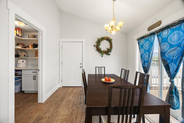 dining area featuring a chandelier, wood finished floors, vaulted ceiling, and baseboards