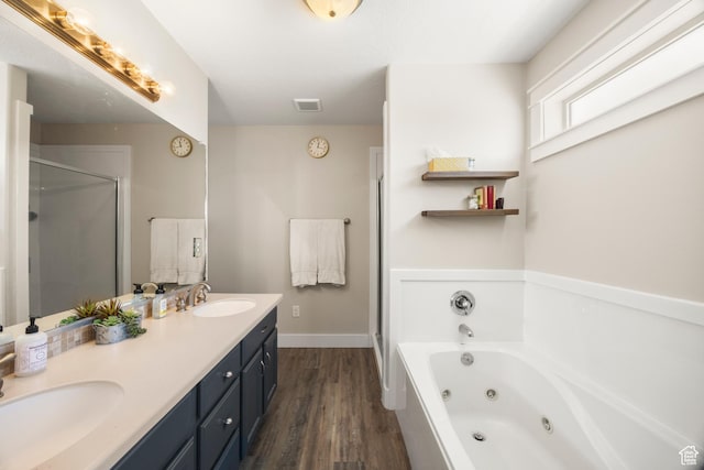 bathroom with wood finished floors, a whirlpool tub, a stall shower, double vanity, and baseboards