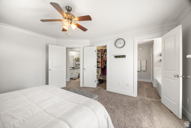 bedroom with a walk in closet, carpet floors, ornamental molding, a closet, and ensuite bath