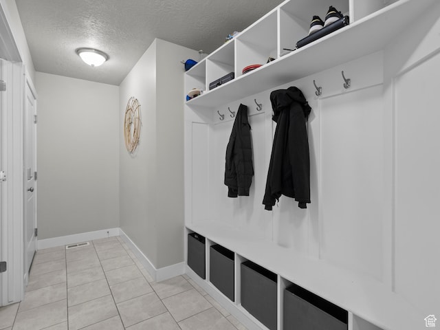 mudroom with a textured ceiling, baseboards, and light tile patterned floors
