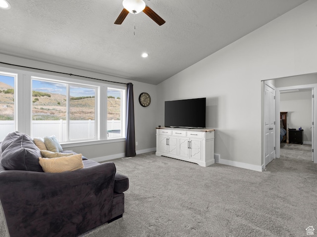 living room featuring lofted ceiling, ceiling fan, a textured ceiling, light carpet, and baseboards