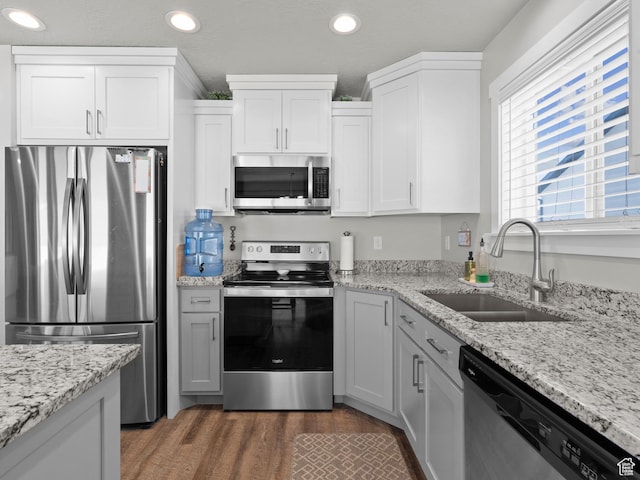 kitchen featuring stainless steel appliances, a sink, recessed lighting, wood finished floors, and white cabinetry