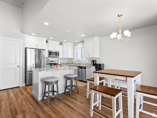 kitchen featuring stainless steel appliances, a chandelier, light wood-style floors, recessed lighting, and a kitchen island