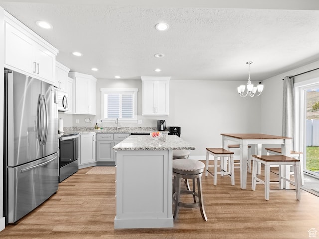 kitchen with stainless steel appliances, light wood-style flooring, a breakfast bar, white cabinetry, and recessed lighting