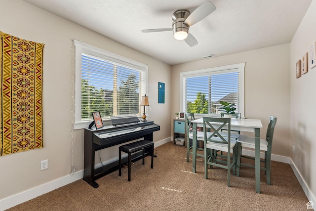 carpeted dining space featuring a ceiling fan, a desk, and baseboards