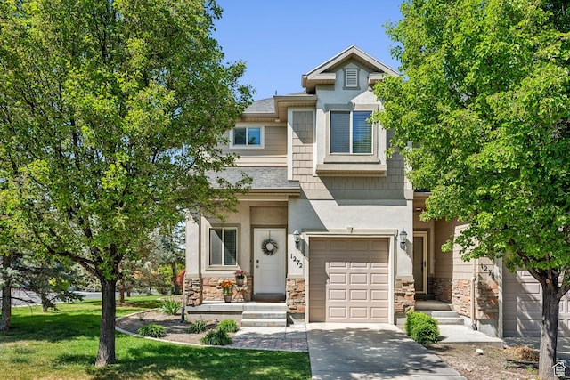 townhome / multi-family property with stone siding, an attached garage, driveway, and a front lawn