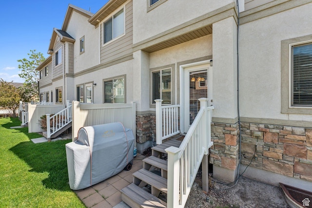 back of house featuring stone siding, stucco siding, and a yard