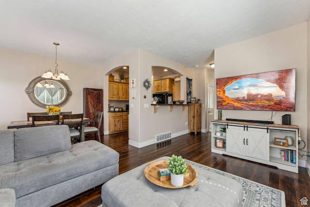 living room featuring arched walkways, a chandelier, dark wood-type flooring, and baseboards