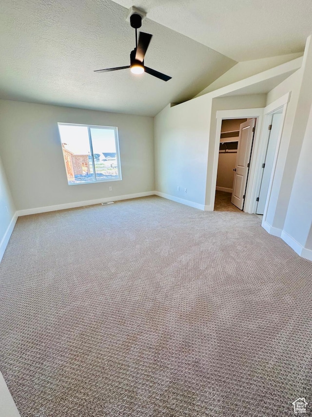 566 W 1860 N, Tooele, UT 84074 - unfurnished bedroom featuring light colored carpet, lofted ceiling, baseboards, a walk in closet, and a textured ceiling
