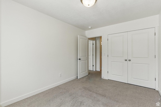 unfurnished bedroom with carpet floors, baseboards, a closet, and a textured ceiling