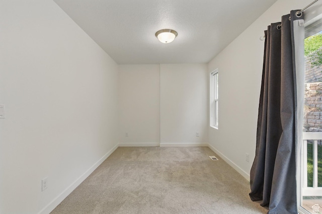 unfurnished room featuring light colored carpet and baseboards