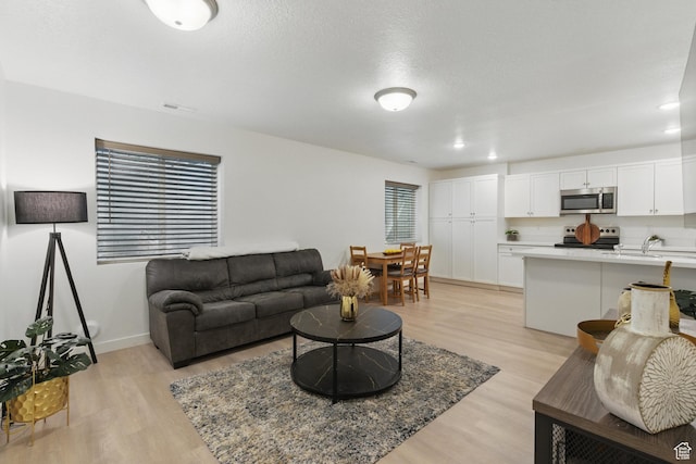 living room with light wood-type flooring, recessed lighting, and baseboards