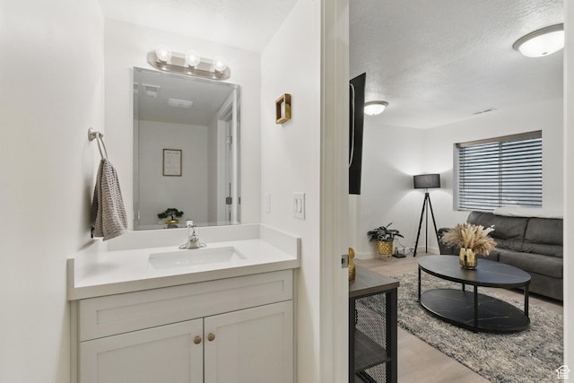 bathroom with wood finished floors, a textured ceiling, and vanity