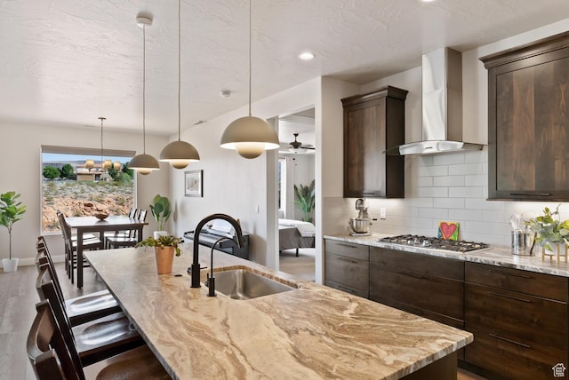 921 N Camino Pico N, Washington, UT 84780 - kitchen with a sink, wall chimney exhaust hood, stainless steel gas cooktop, backsplash, and dark brown cabinetry