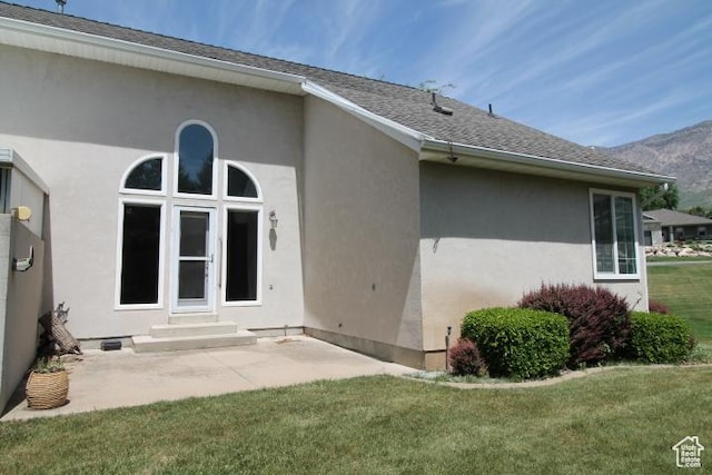 back of house with a yard, stucco siding, a patio area, and a mountain view