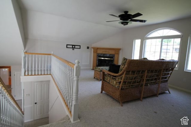 carpeted living area featuring plenty of natural light, ceiling fan, vaulted ceiling, a fireplace, and baseboards