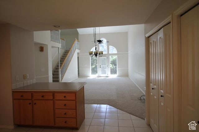 kitchen featuring light colored carpet, a chandelier, light tile patterned flooring, a peninsula, and light countertops