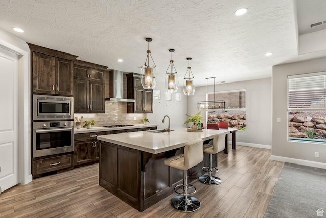 750 W 1860 N, Washington, UT 84780 - kitchen featuring stainless steel appliances, wall chimney exhaust hood, a sink, light wood-style floors, and light countertops