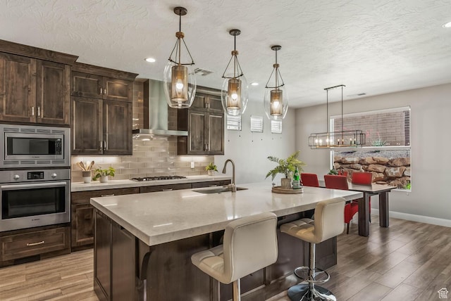 750 W 1860 N, Washington, UT 84780 - kitchen with stainless steel appliances, a sink, wall chimney exhaust hood, light wood-type flooring, and backsplash
