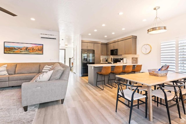 dining space with a wall mounted air conditioner, light wood-type flooring, and recessed lighting