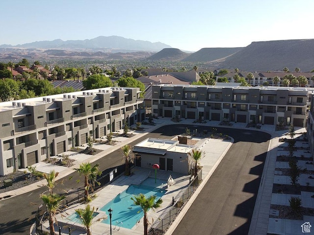 drone / aerial view of a pool area, a mountain backdrop, and apartment complex