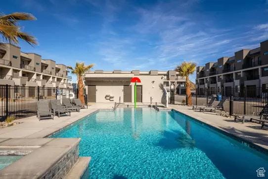 community pool with fence, a patio, and a residential view