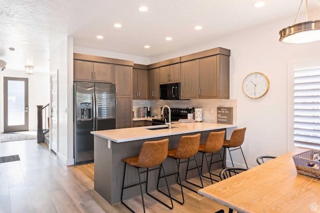 kitchen featuring black appliances, a peninsula, a sink, tasteful backsplash, and recessed lighting