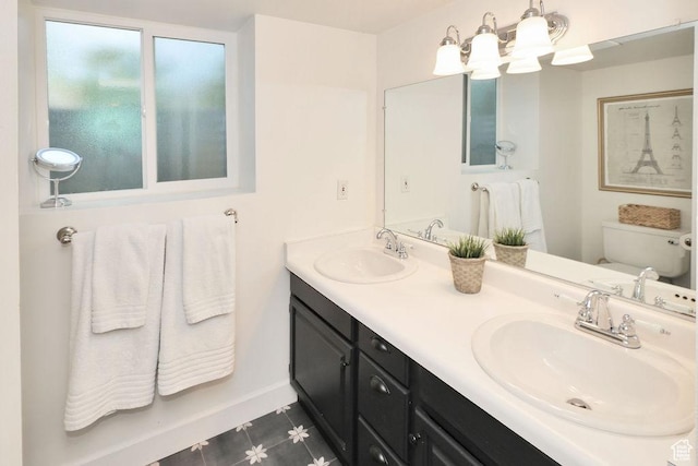 bathroom with toilet, a chandelier, double vanity, and baseboards