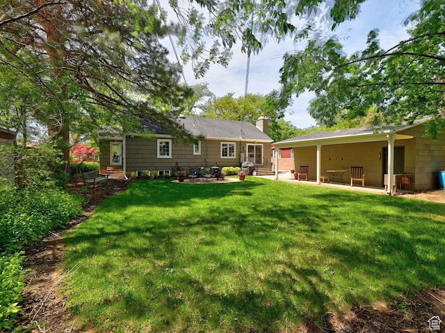 back of house with a patio, a chimney, entry steps, and a yard