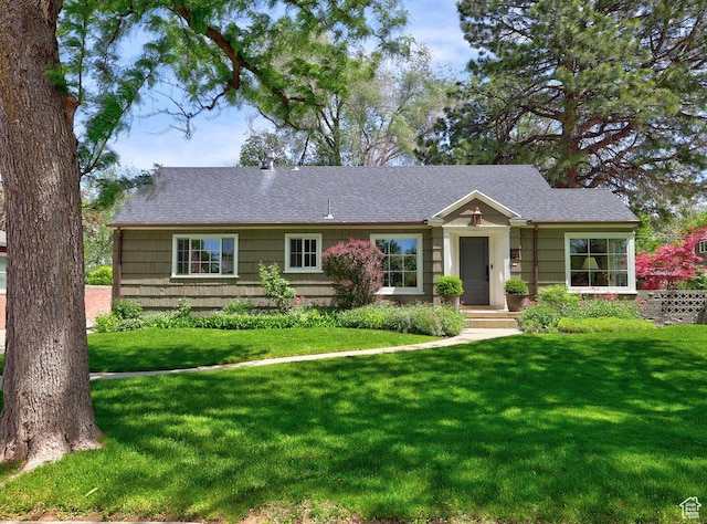 ranch-style home featuring a front yard and a shingled roof