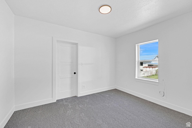 empty room with dark carpet and baseboards